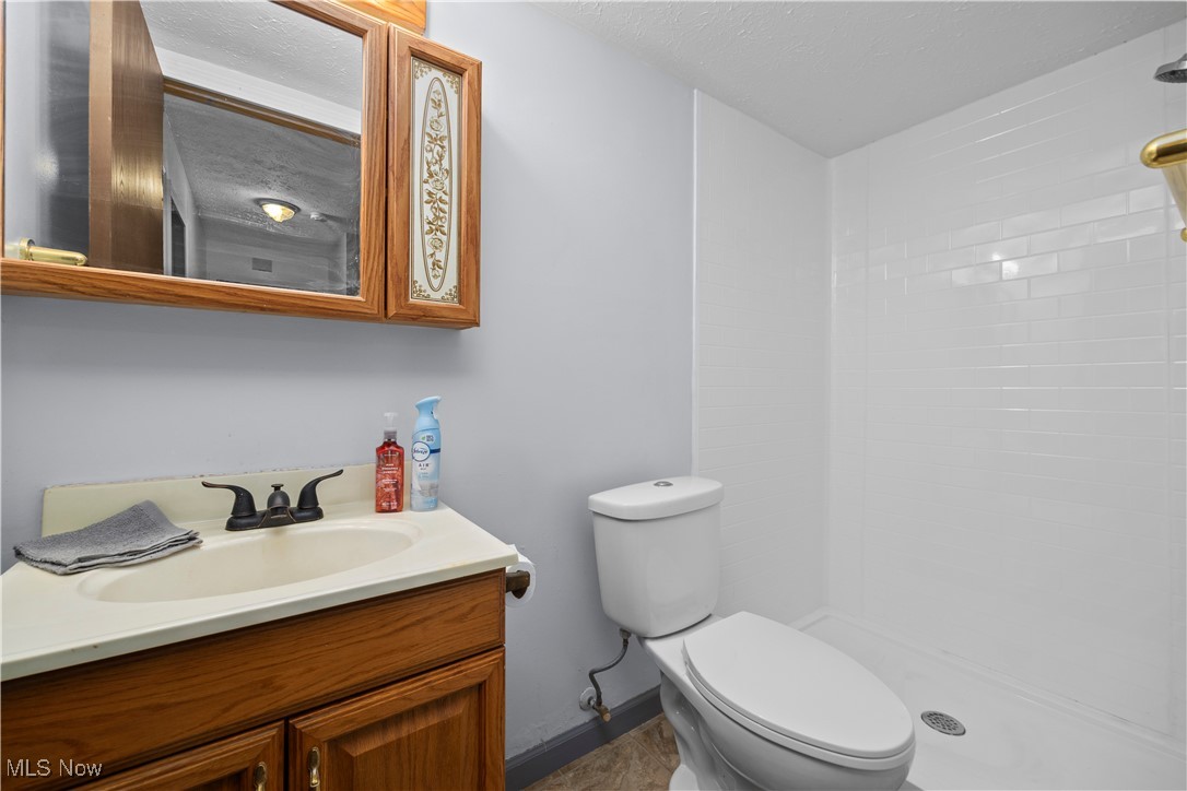 29379 Detroit Road Westlake, OH 44145 - Photo 17 of 23 Full bathroom featuring vanity, a textured ceiling, and tiled shower