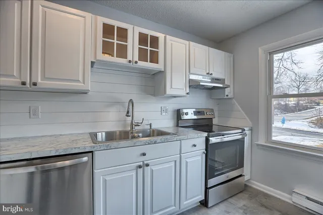 a kitchen with stainless steel appliances granite countertop white cabinets and window