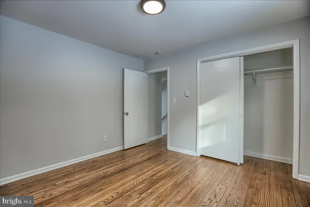 a view of an empty room with wooden floor and window