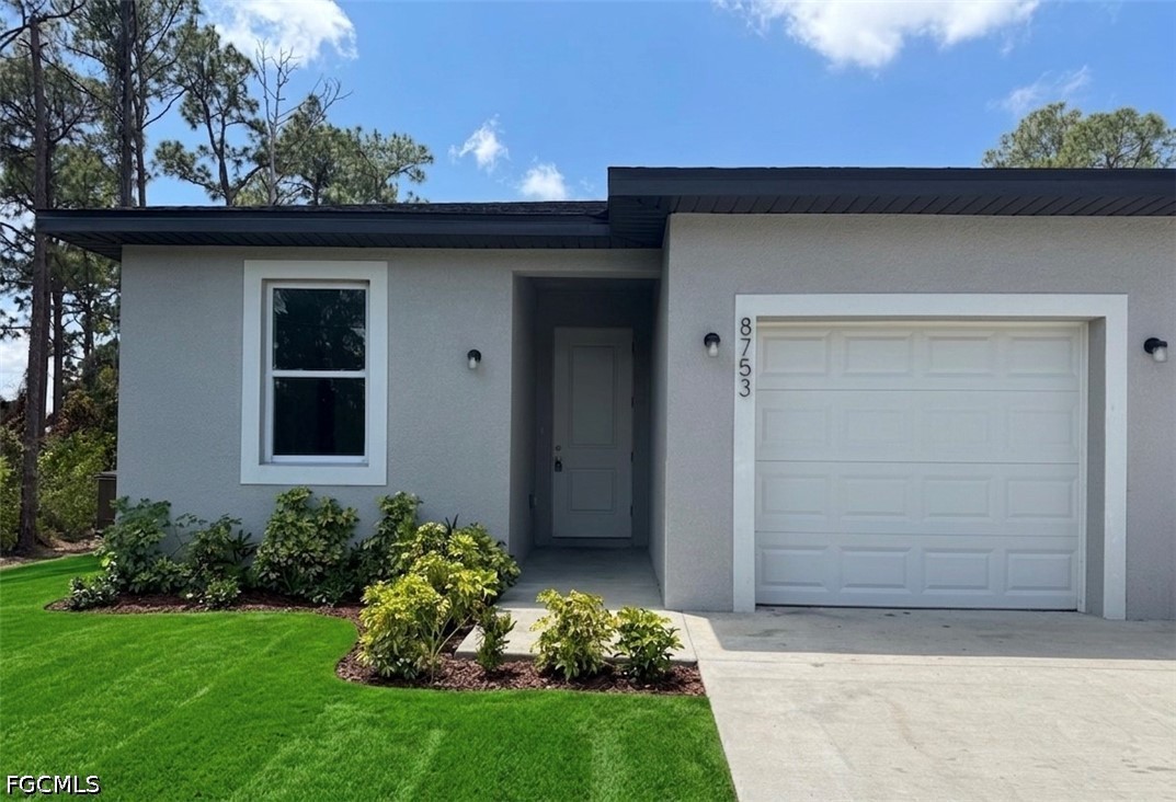 8753 Buckingham Road Lehigh Acres, FL 33971 - Photo 2 of 13 a front view of a house with a garden