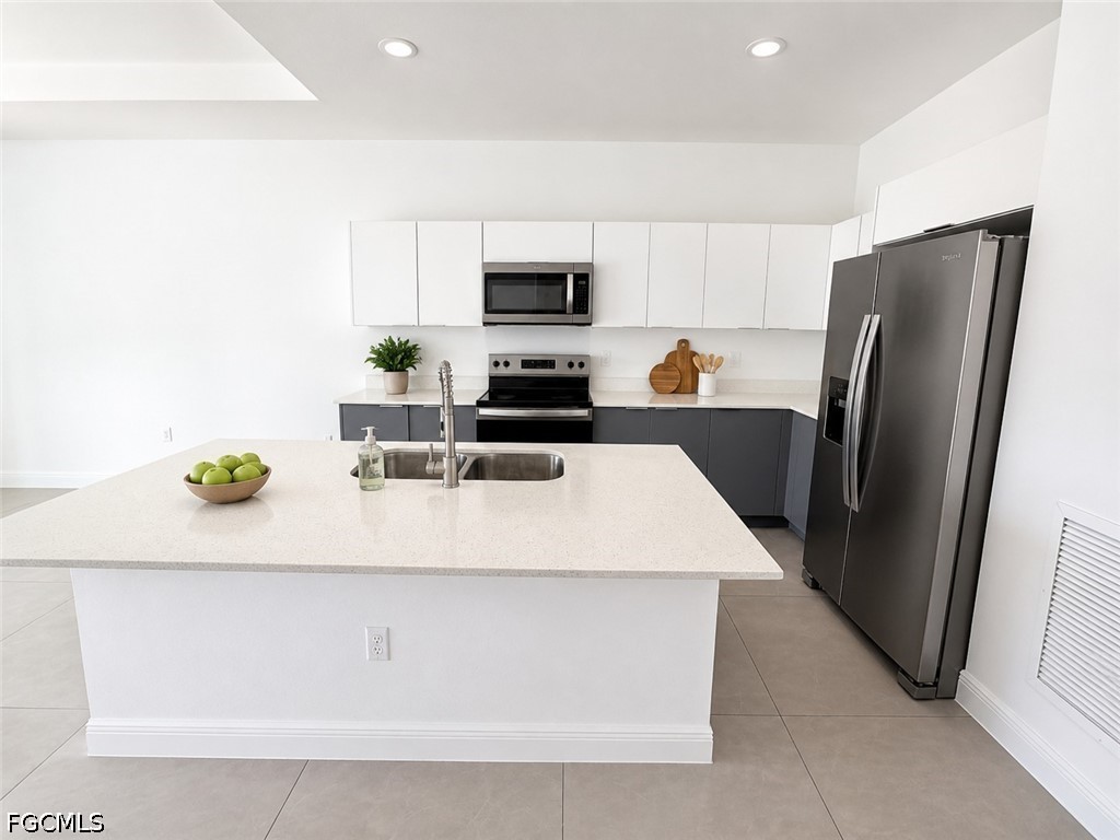8753 Buckingham Road Lehigh Acres, FL 33971 - Photo 4 of 13 a kitchen with stainless steel appliances a refrigerator a sink a stove a microwave a counter top and cabinets