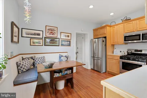 a kitchen with stainless steel appliances granite countertop a refrigerator a stove a sink a dining table and chairs with wooden floor
