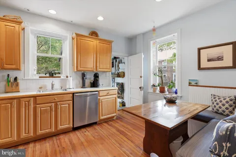 a kitchen with granite countertop a sink cabinets wooden floor and stainless steel appliances