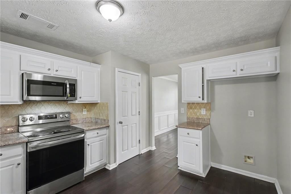 1259 Maxey Court Winder, GA 30680 - Photo 11 of 30 a kitchen with stainless steel appliances white cabinets and a stove