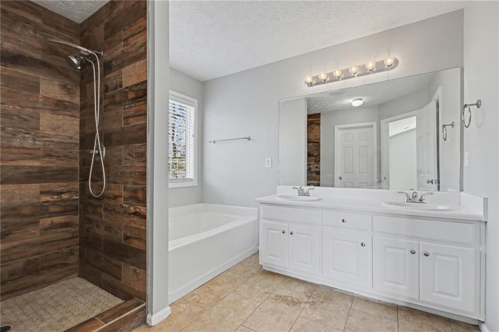 1259 Maxey Court Winder, GA 30680 - Photo 17 of 30 a bathroom with a double vanity sink a toilet a mirror and shower