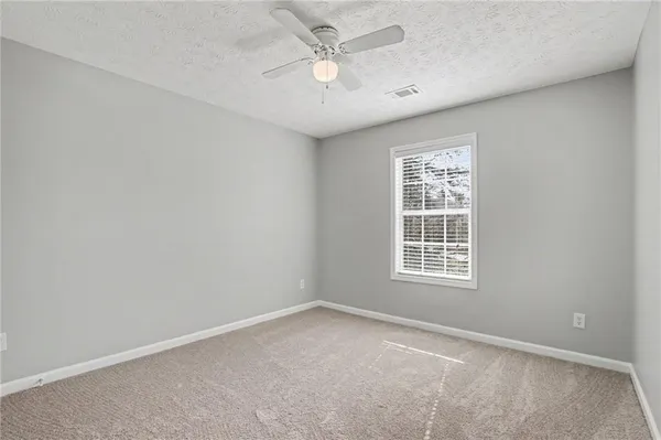 an empty room with a window and a ceiling fan