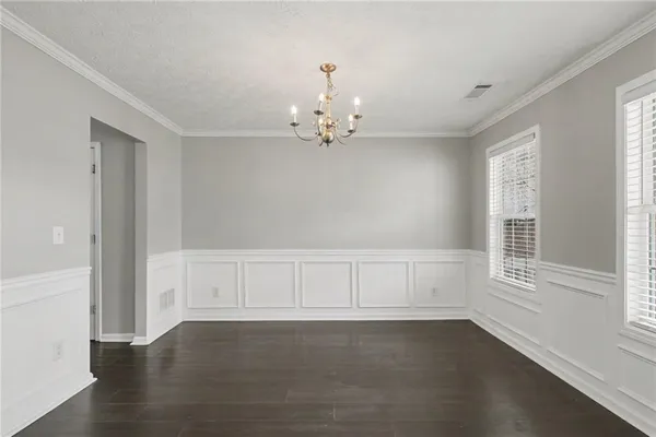 an empty room with wooden floor cabinet and windows