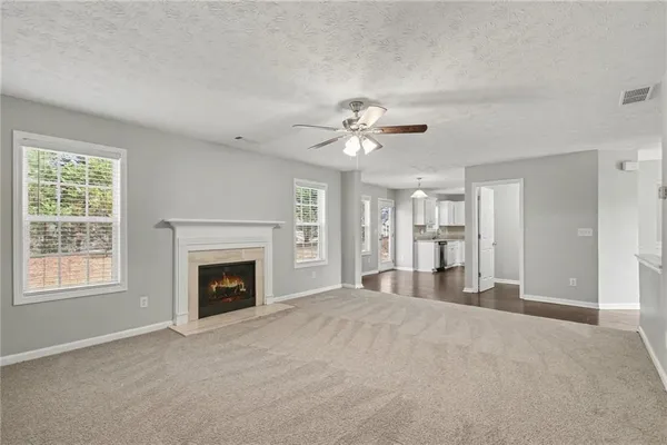 a view of an empty room with a fireplace and chandelier fan
