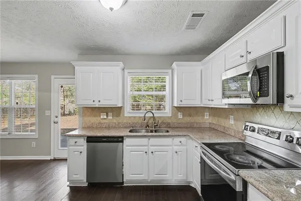 a kitchen with stainless steel appliances granite countertop a sink stove and cabinets