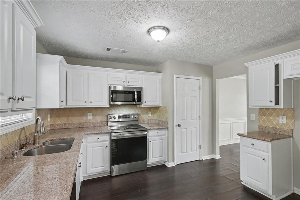 1259 Maxey Court Winder, GA 30680 - Photo 10 of 30 a kitchen with stainless steel appliances granite countertop a refrigerator sink and white cabinets