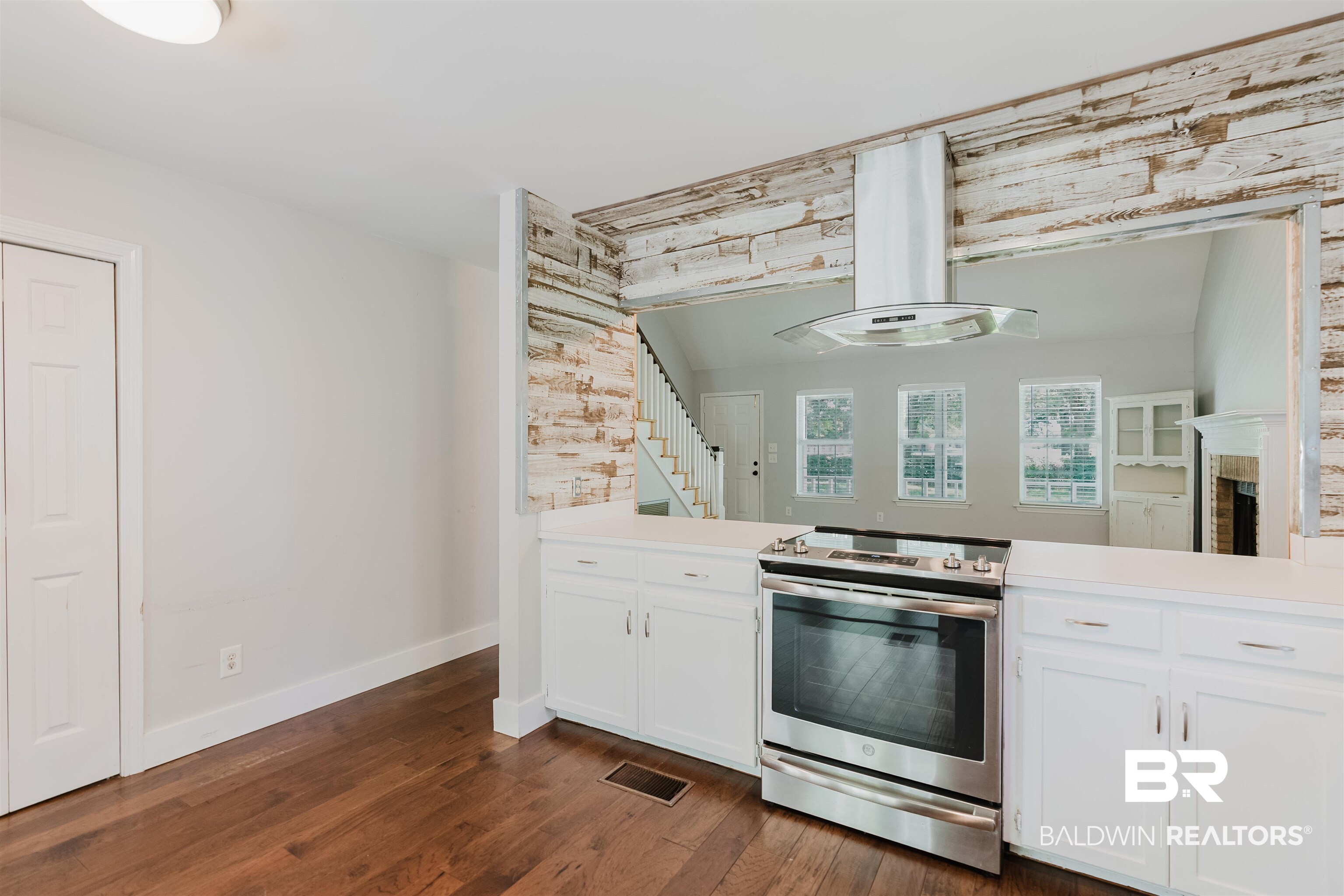 20460 Bishop Road Fairhope, AL 36532 - Photo 27 of 41 Kitchen with stainless steel range with electric stovetop, island range hood, dark wood finished floors, baseboards, and white cabinets