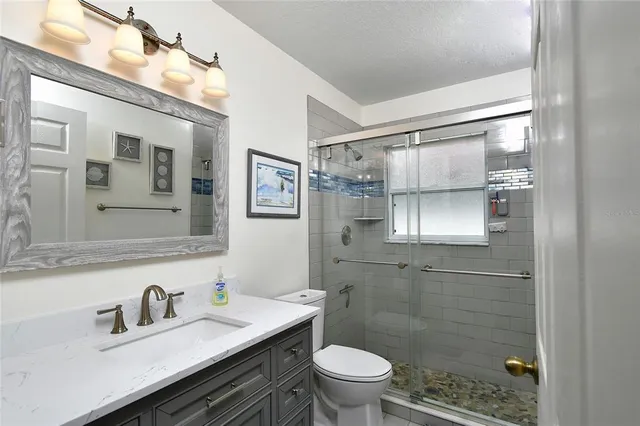 a bathroom with a granite countertop sink toilet a mirror and shower