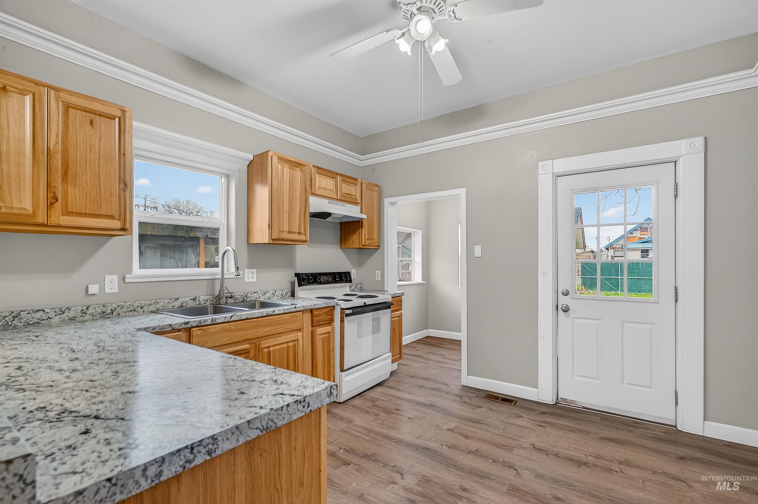 833 8th Street Clarkston, WA 99403 - Photo 12 of 40 Kitchen featuring white electric range oven, light countertops, light wood finished floors, under cabinet range hood, and ceiling fan