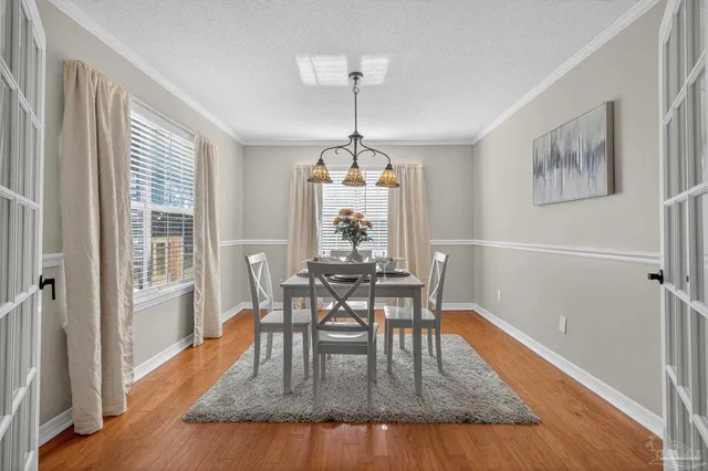 a dining room with wooden floor a chandelier a wooden table and chairs