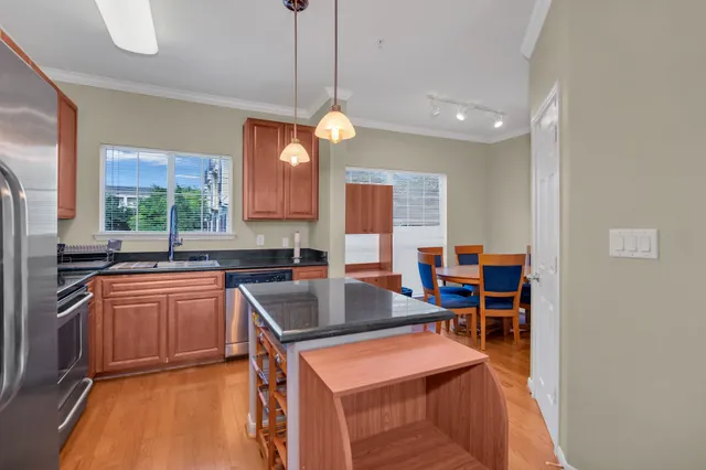 a kitchen with stainless steel appliances granite countertop wooden cabinets a stove a sink and a island