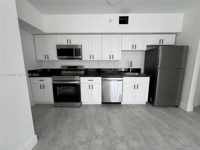 a kitchen with refrigerator and white cabinets