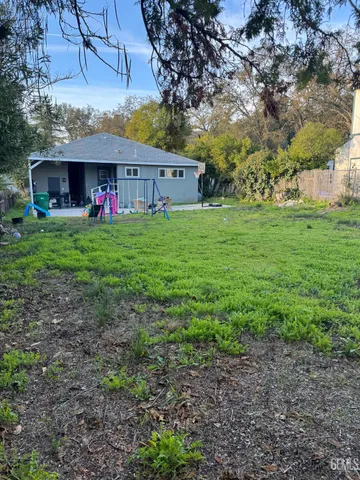 a view of a big yard in front of a house with a large tree