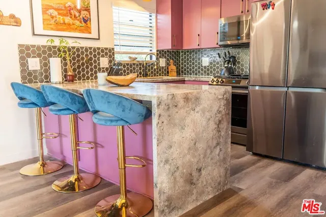 a kitchen with stainless steel appliances kitchen island granite countertop a refrigerator and stove