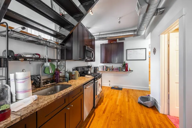 a view of a hallway with wooden floor and a kitchen