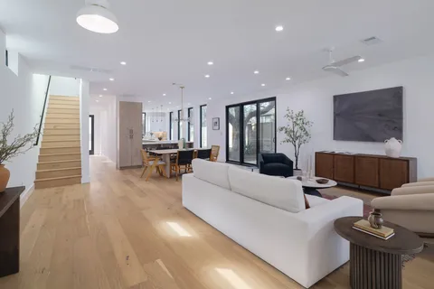 a living room with furniture kitchen view and a chandelier