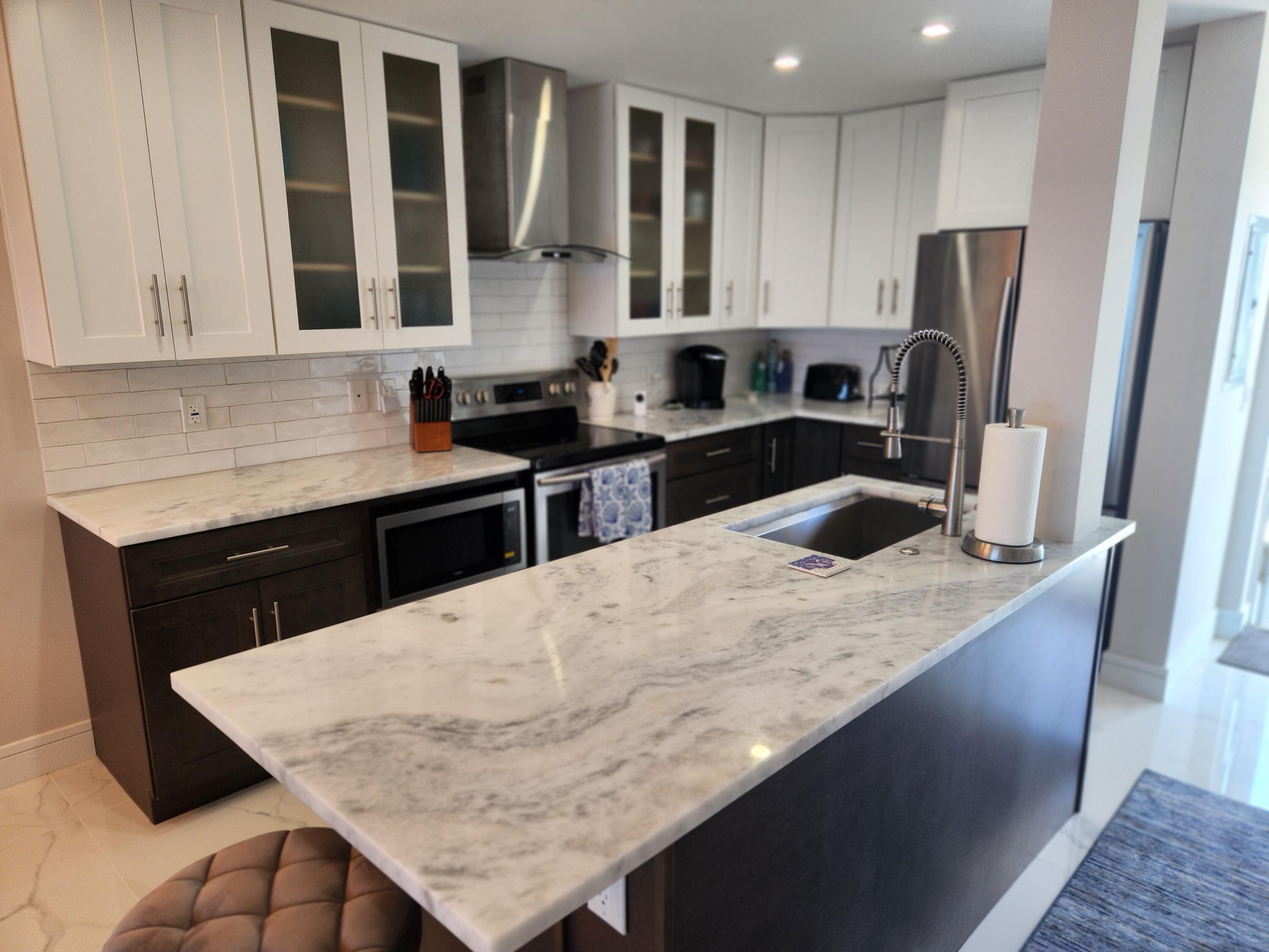 3101 South Ocean Boulevard, Unit 812 Highland Beach, FL 33487 - Photo 9 of 24 a kitchen with stainless steel appliances granite countertop a sink a stove and a refrigerator