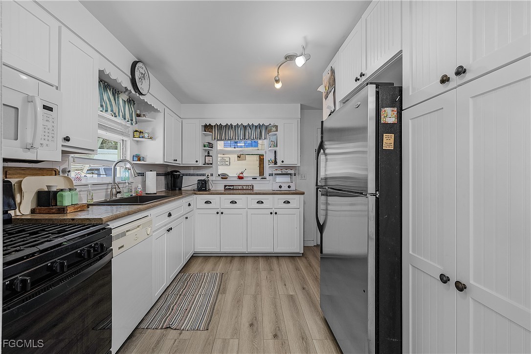 15925 Quail Trail Bokeelia, FL 33922 - Photo 10 of 26 a kitchen with white cabinets and stainless steel appliances