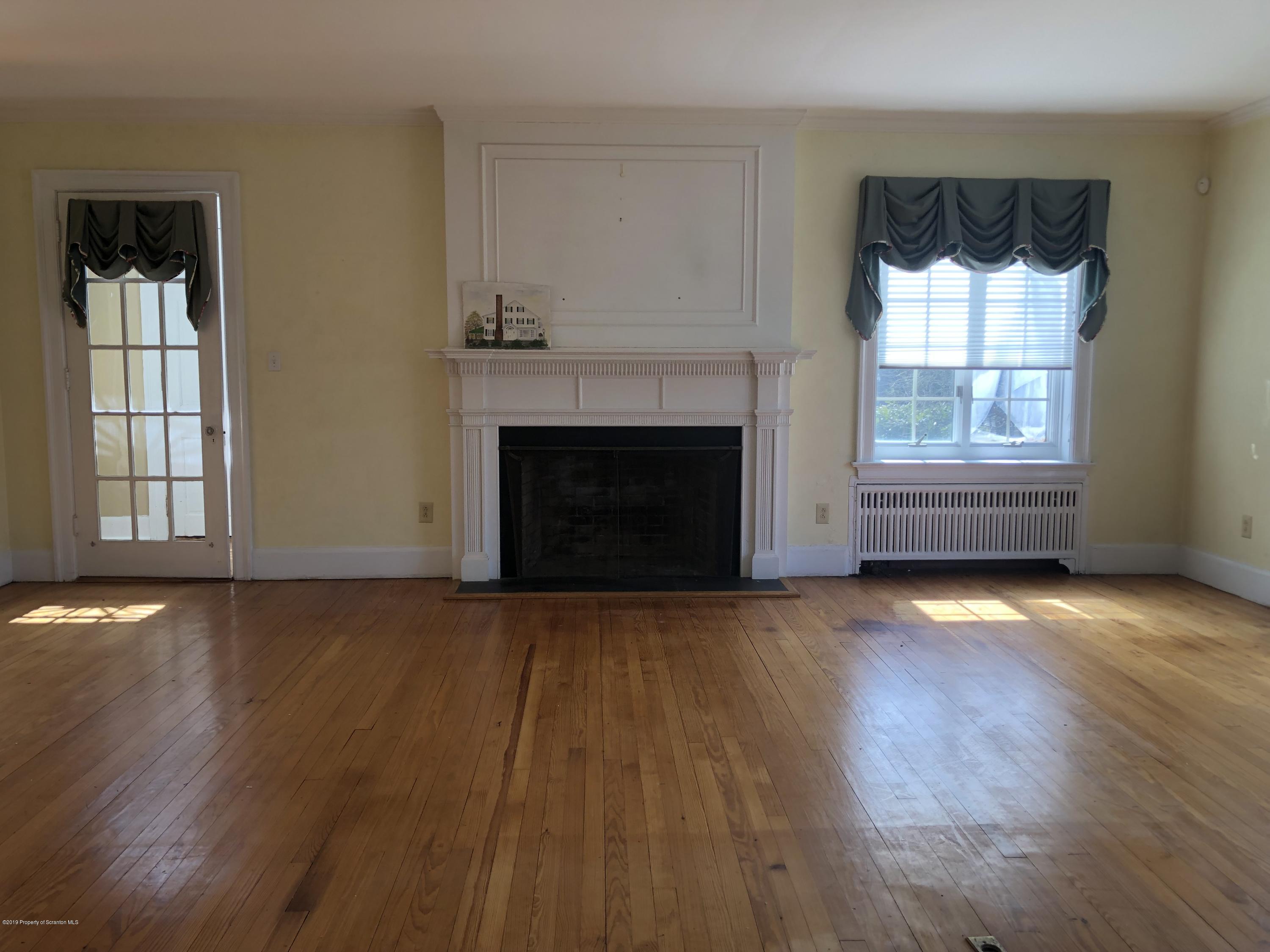 105 Noble Road Clarks Summit, PA 18411 - Photo 6 of 11 an empty room with wooden floor fireplace and windows