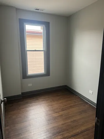 a view of an empty room with wooden floor and closet