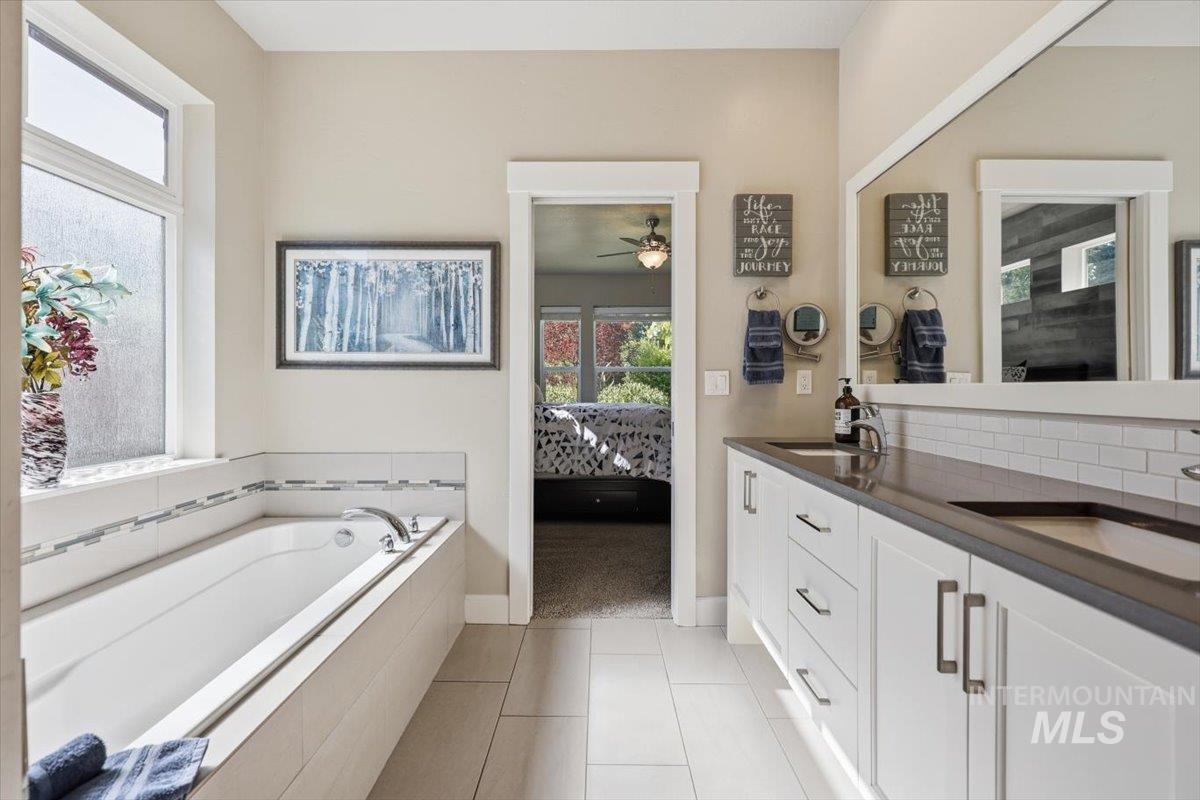 1303 West Brando Street Meridian, ID 83646 - Photo 26 of 49 Bathroom featuring a built-in soaking tub with tile surround, a dual vanity with undermount sinks, and light-toned tile flooring
