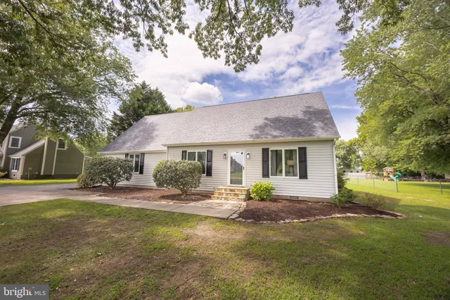 a front view of a house with garden and trees