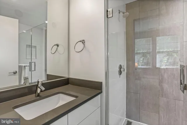 a bathroom with a granite countertop sink a mirror and shower