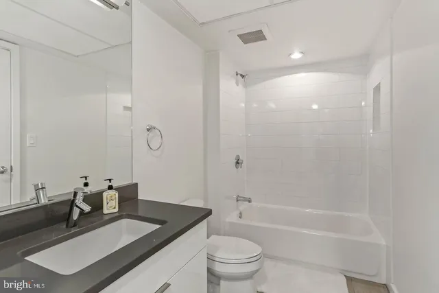 a bathroom with a granite countertop sink a toilet and shower
