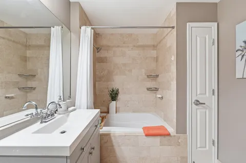 a bathroom with a tub sink vanity and mirror