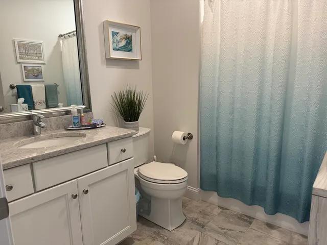 a bathroom with a granite countertop sink toilet and a mirror