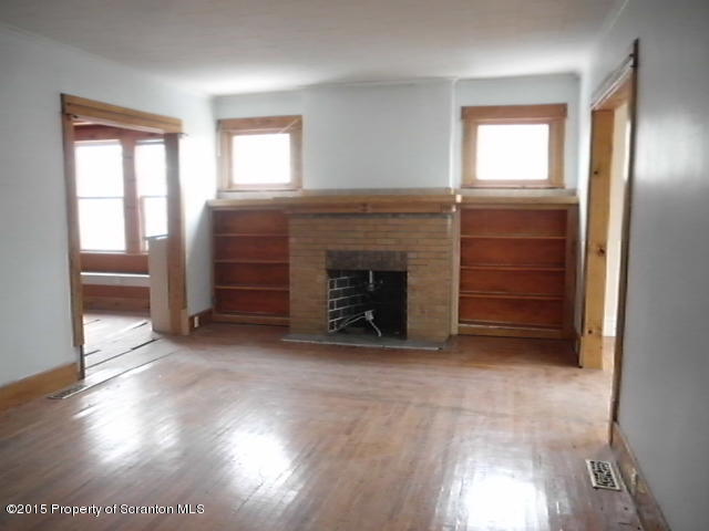 139 Spring Street Carbondale, PA 18407 - Photo 4 of 25 an empty room with windows cabinet and fireplace