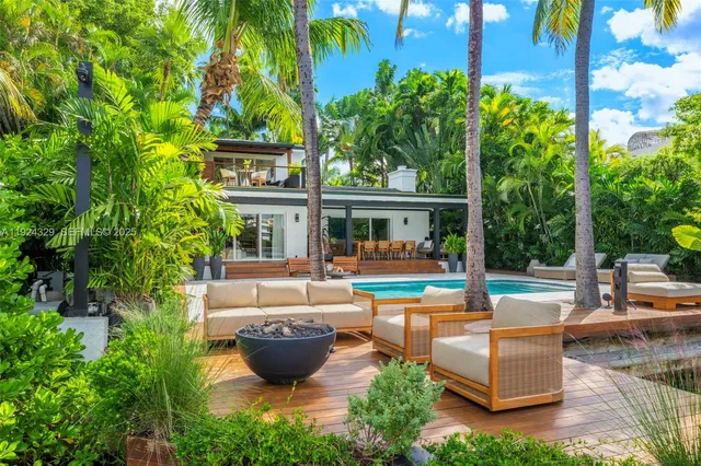 a view of a swimming pool with couches and table and chairs under an umbrella