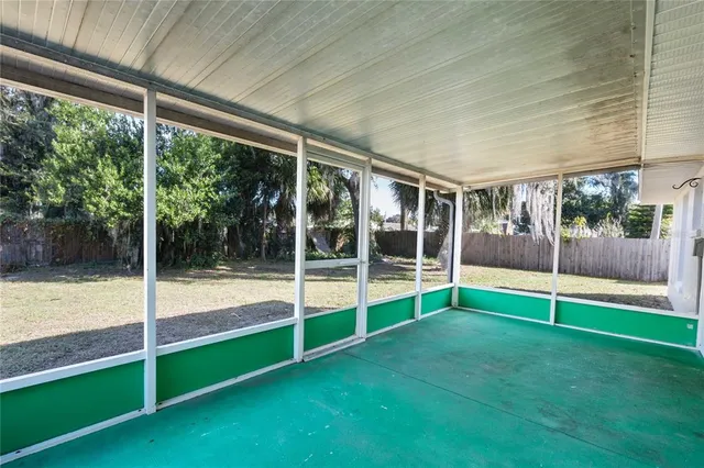 a view of an empty room with floor to ceiling windows with yard