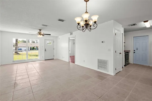 a view of a livingroom with a chandelier fan and refrigerator