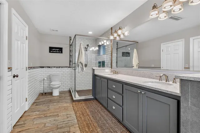 a spacious bathroom with a double vanity sink a large mirror and a shower