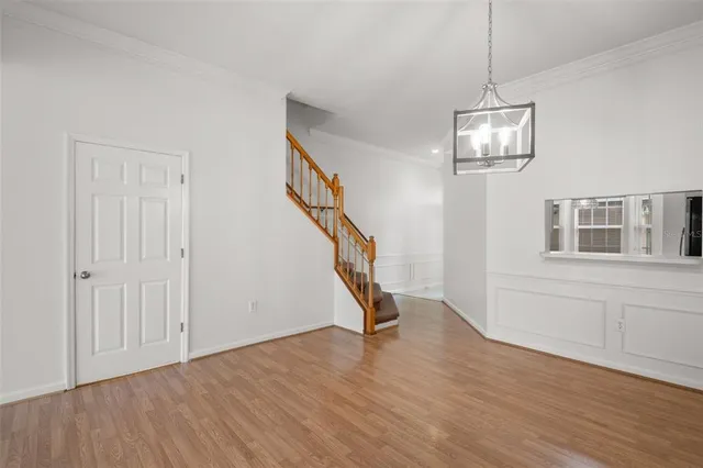 a view of empty room with wooden floor chandelier and windows