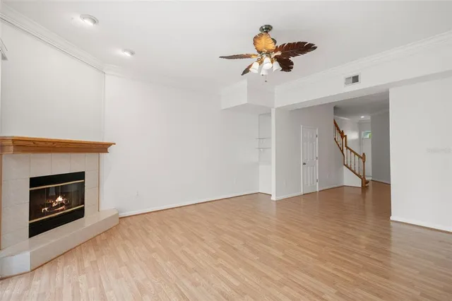 a view of an empty room with a fireplace and a ceiling fan