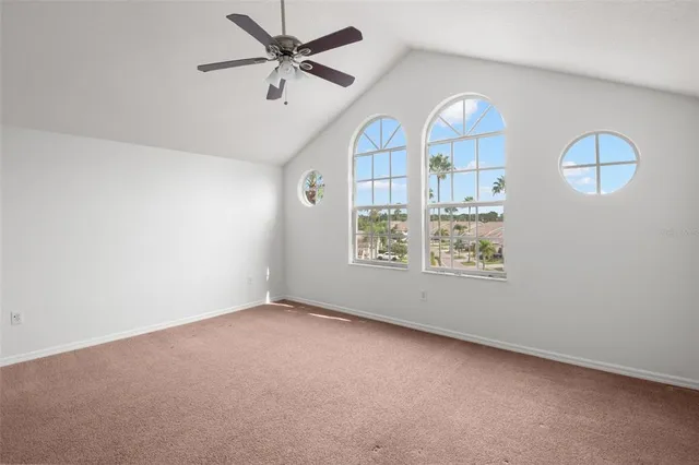 an empty room with windows and ceiling fan