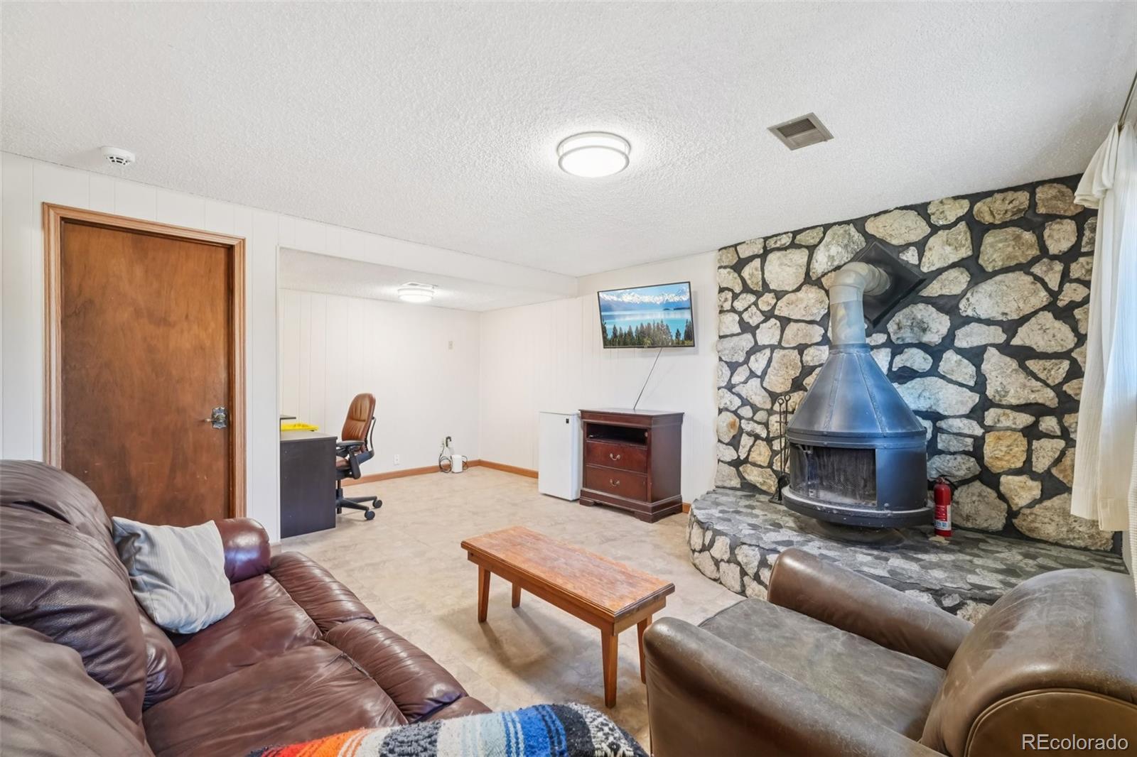 6277 Reed Court Arvada, CO 80003 - Photo 17 of 40 a living room with furniture a fireplace and a flat screen tv