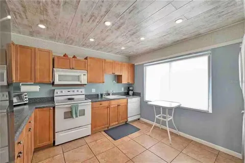 a kitchen with stainless steel appliances granite countertop a stove top oven a sink dishwasher and white cabinets with wooden floor