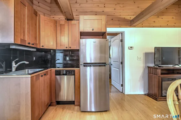 a kitchen with stainless steel appliances granite countertop a stove top oven a sink a dining table and chairs with wooden floor