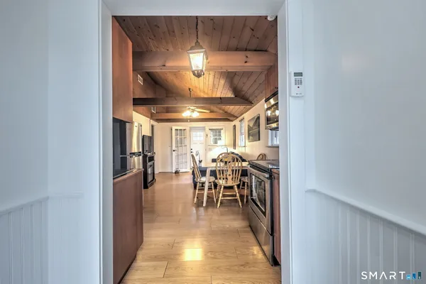 a view of a kitchen with stainless steel appliances granite countertop a stove top oven a refrigerator a dining table and chairs with wooden floor