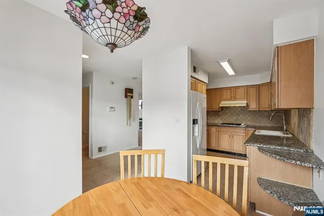 a kitchen with stainless steel appliances granite countertop a refrigerator a stove a sink dishwasher and white cabinets with wooden floor