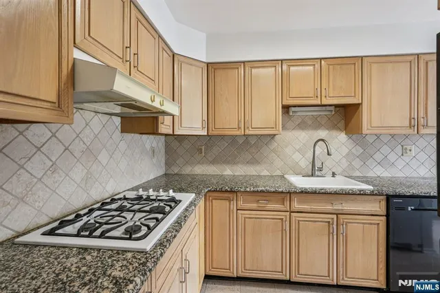 a kitchen with granite countertop a sink stove and cabinets