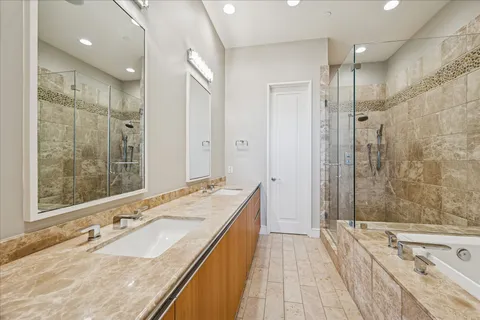 a spacious bathroom with a granite countertop double vanity sink a large mirror and shower