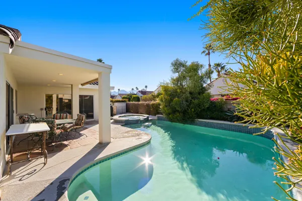 a view of a swimming pool with lawn chairs under an umbrella